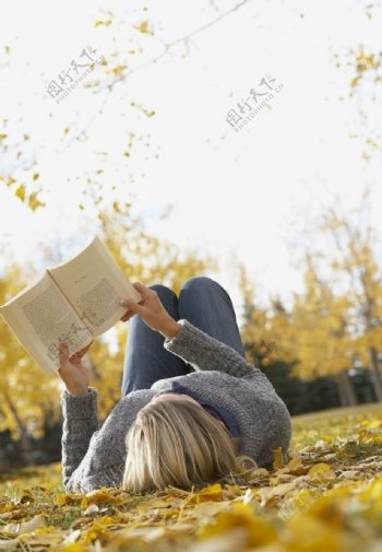 躺在秋天落叶上看书的女孩图片