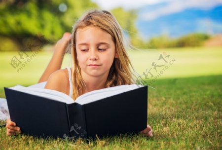 趴在草地上看书的外国小女孩图片