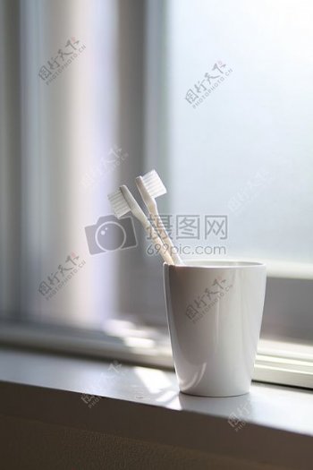 两个白色的牙刷内的白色陶瓷杯