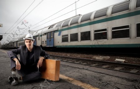 火车旁手扶箱子的旅游男人图片