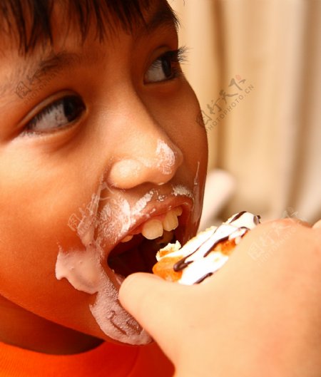 一个混乱的面吃一个奶油蛋糕的孩子
