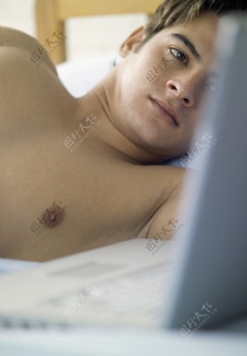 睡在床上上网的男人图片