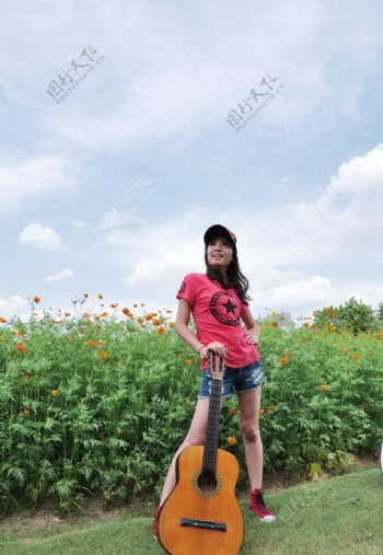 美女在花丛弹吉他图片