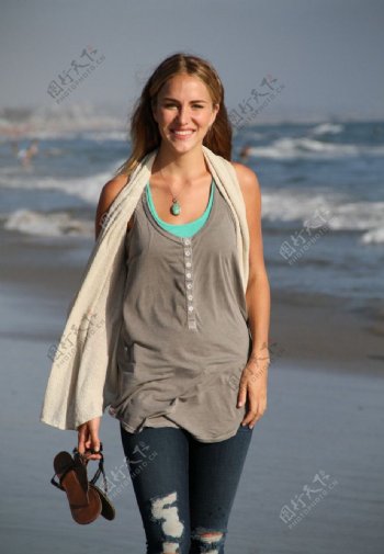 在海滩上拎着鞋子走路的美女图片