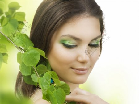 绿叶旁的彩妆女人图片