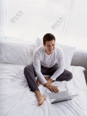 坐在床上玩电脑的男人图片