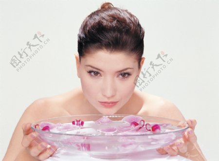 女人端着一盆泡有花瓣的水图片