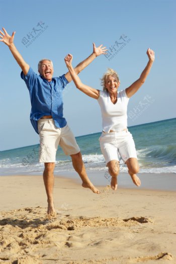 沙滩上的跳跃的老人夫妇图片