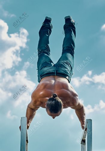 蓝天下倒立的肌肉男人图片