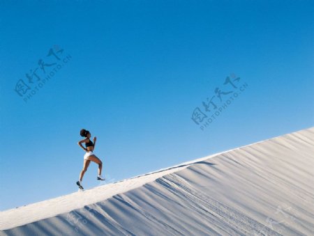 沙漠中背着阳光奔跑的女人图片