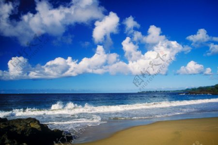海岸上卷起的浪花和漂浮的云朵图片