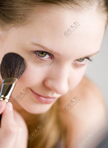 用刷子在脸上化妆的女孩图片图片