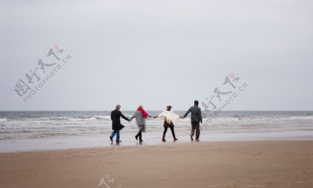 手牵手走在海边的一家人图片