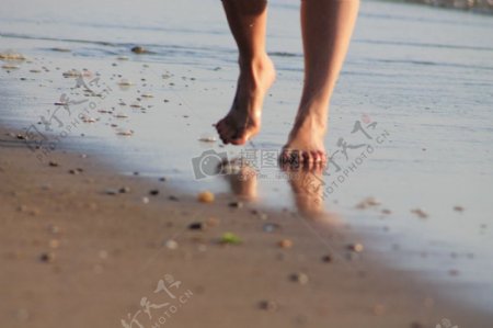 赤脚走在沙滩上的人