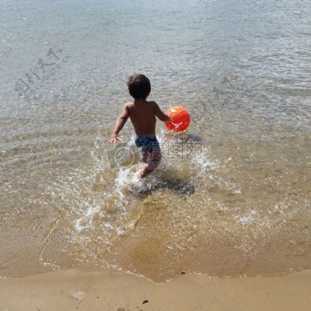 浅水滩玩球的小男孩