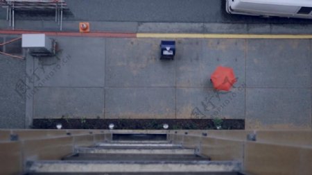 实拍办公楼前撑着红伞走过的人视频素材